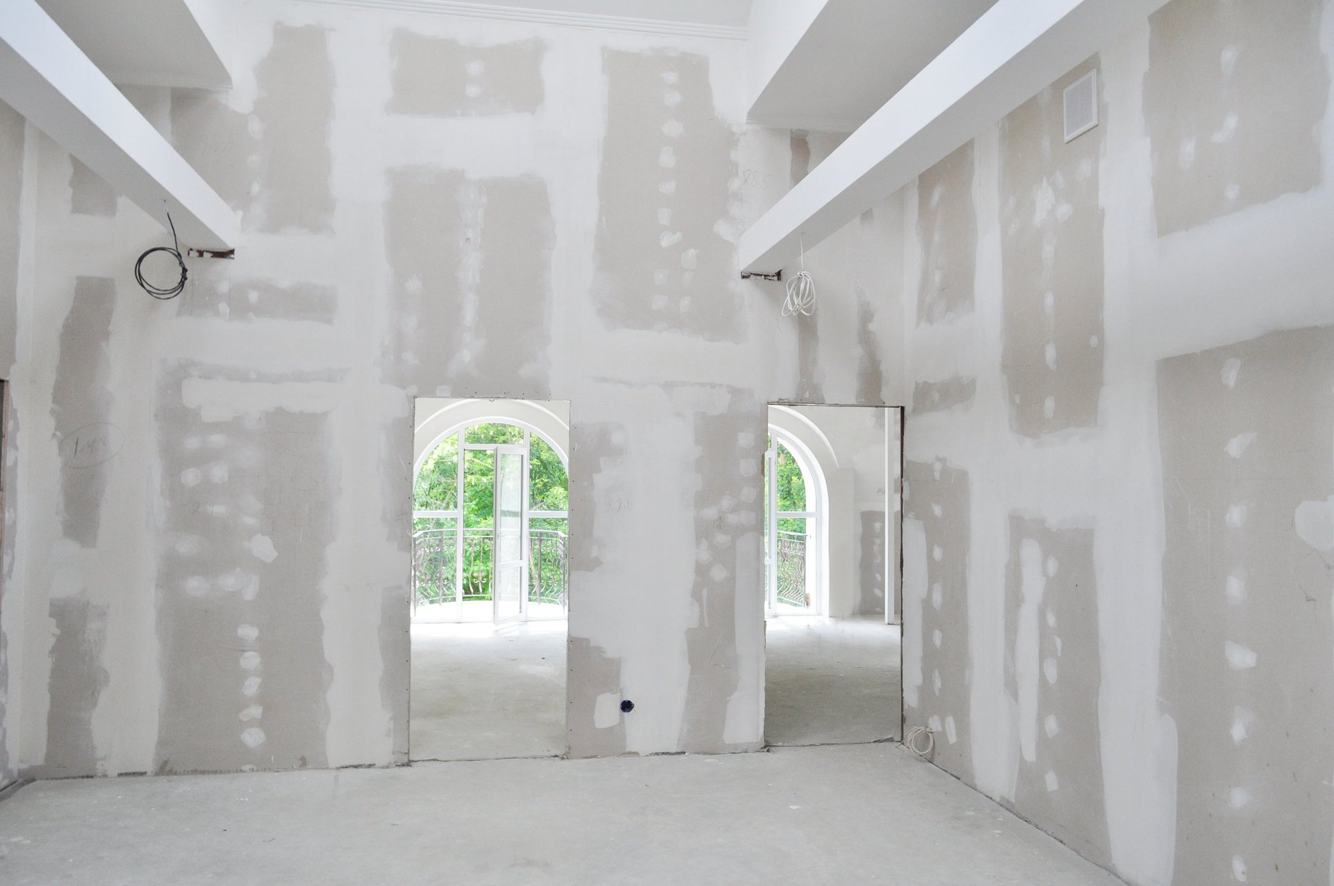 Unpainted interior of a new home under construction, showcasing unfinished drywall, and construction materials. Ideal for illustrating the building process and home improvement.